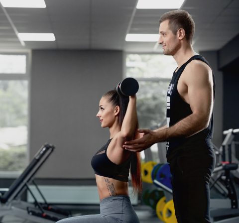 Trainer assisting client on a machine